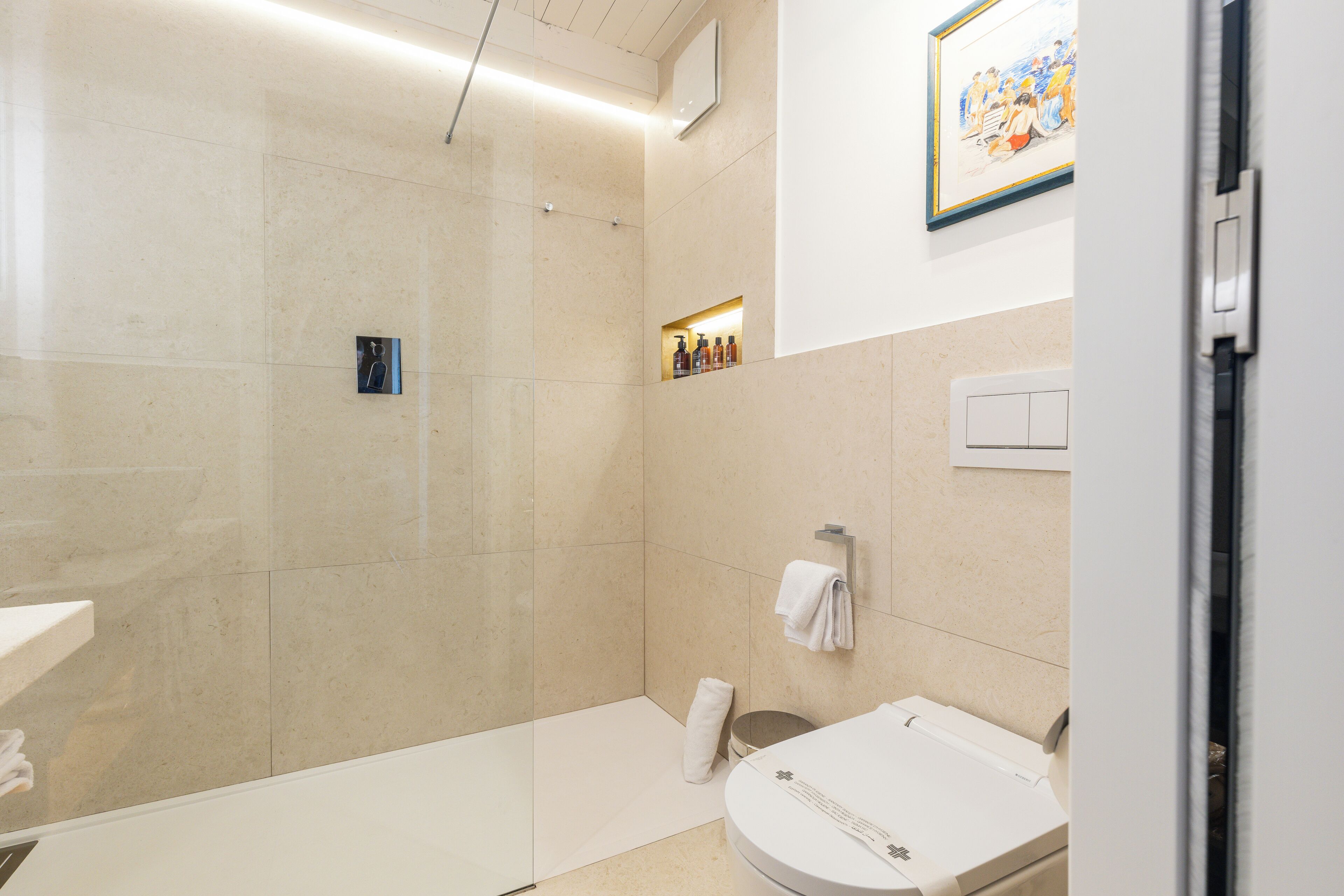 A modern bathroom with a glass-enclosed shower, a white sink, and a towel rack.