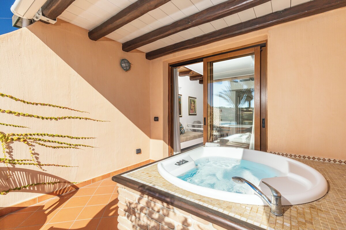 A hot tub with a tiled surround, a wooden ceiling, and a sliding glass door leading to an outdoor area.