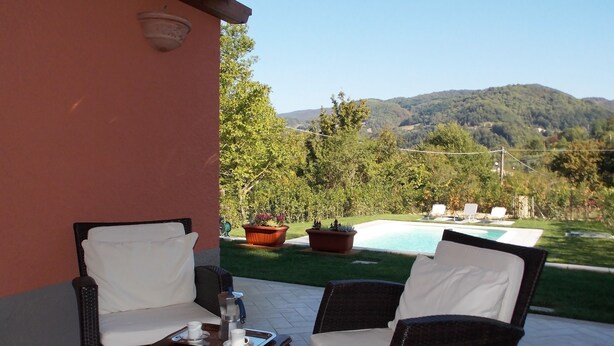 A patio with wicker furniture, a small table with cups, and a view of a swimming pool and hills. - Casa Marcoiano (Scarperia e San Piero)