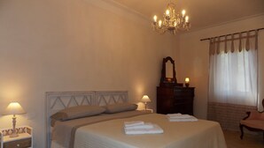 A bedroom with a large bed, bedside lamps, a dresser, a mirror, and a window with curtains. - Casa Marcoiano (Scarperia e San Piero)