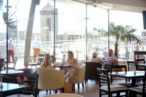 A café with tables and chairs, large windows, and a view of buildings. - Ice House Apartments (Swansea)