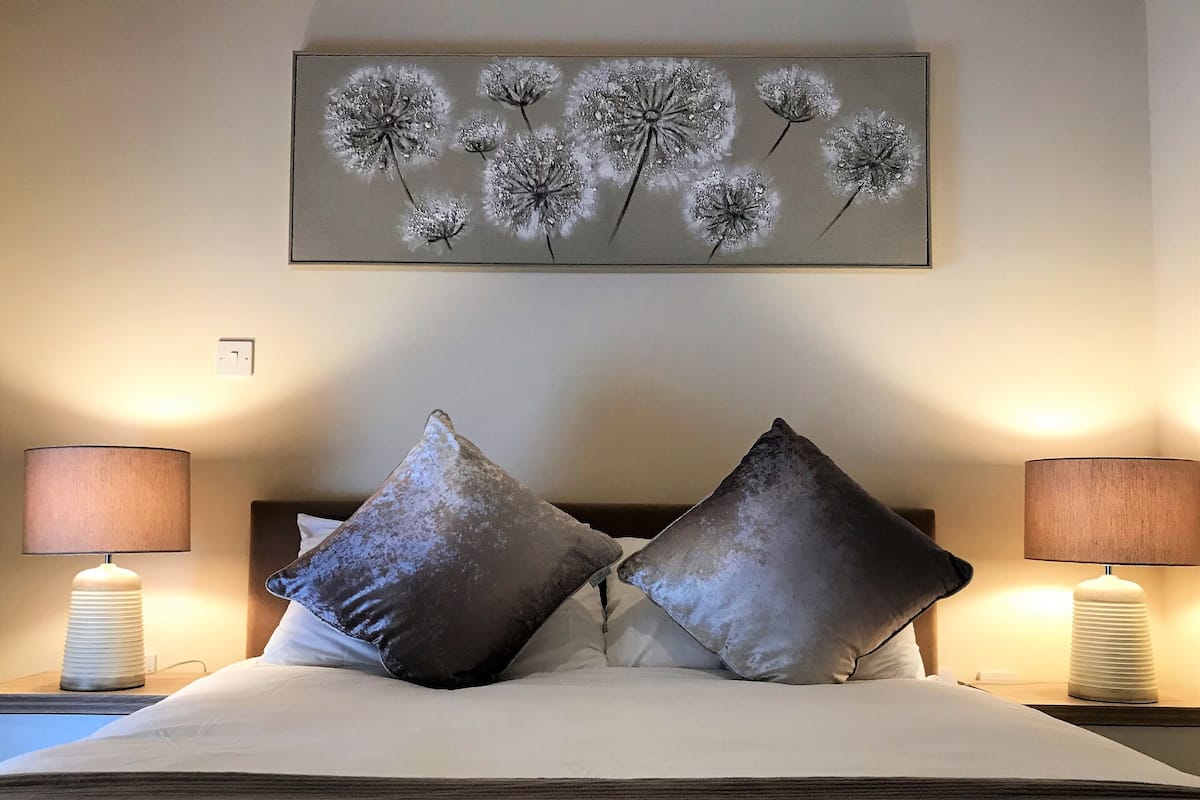 A neatly made bed with two pillows and a framed artwork above it.