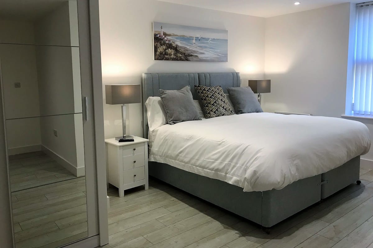 A bedroom with a bed, nightstands, a painting, and a window.
