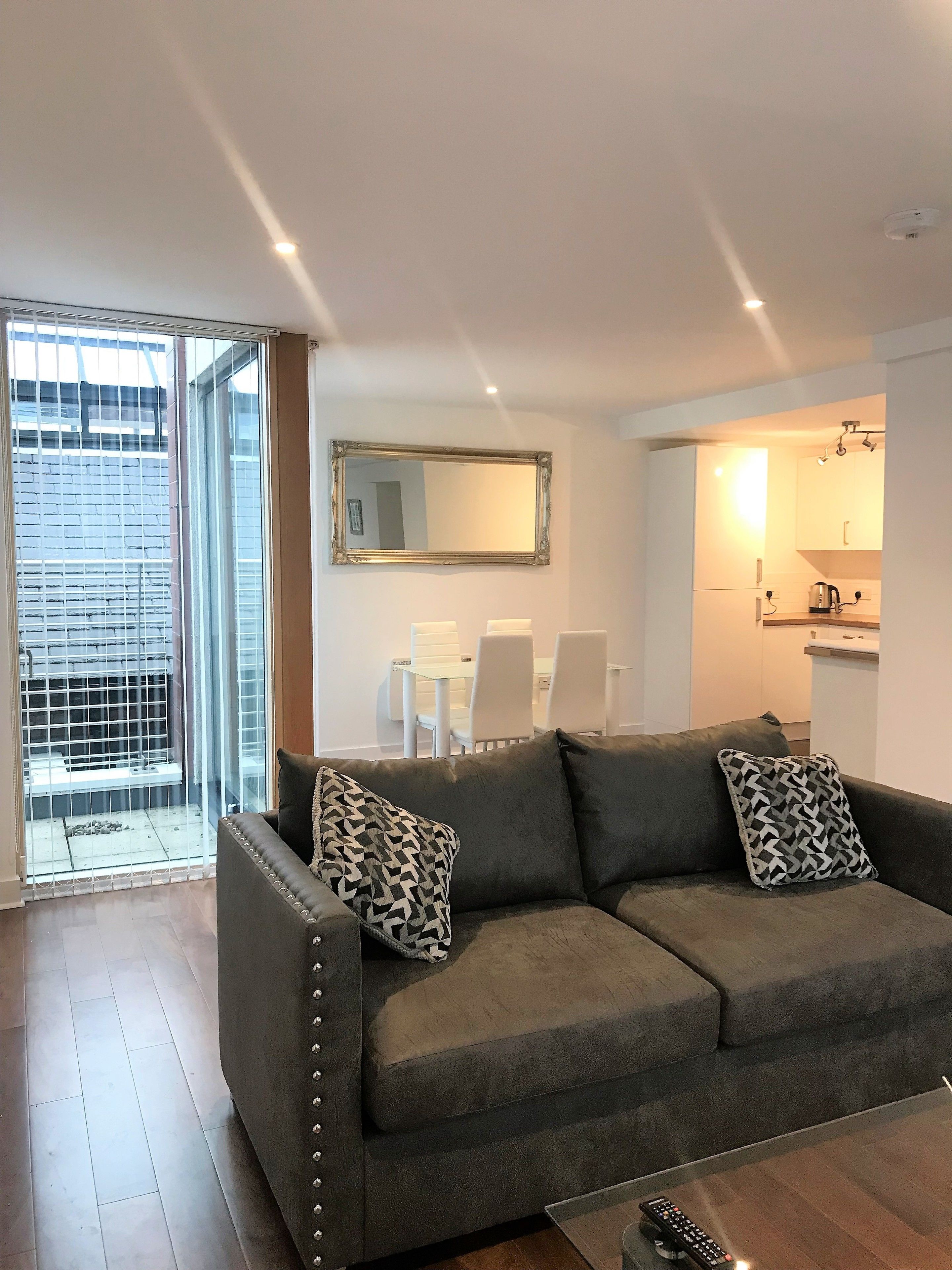 A living room with a grey sofa, a coffee table, and a dining area with a white table and chairs.