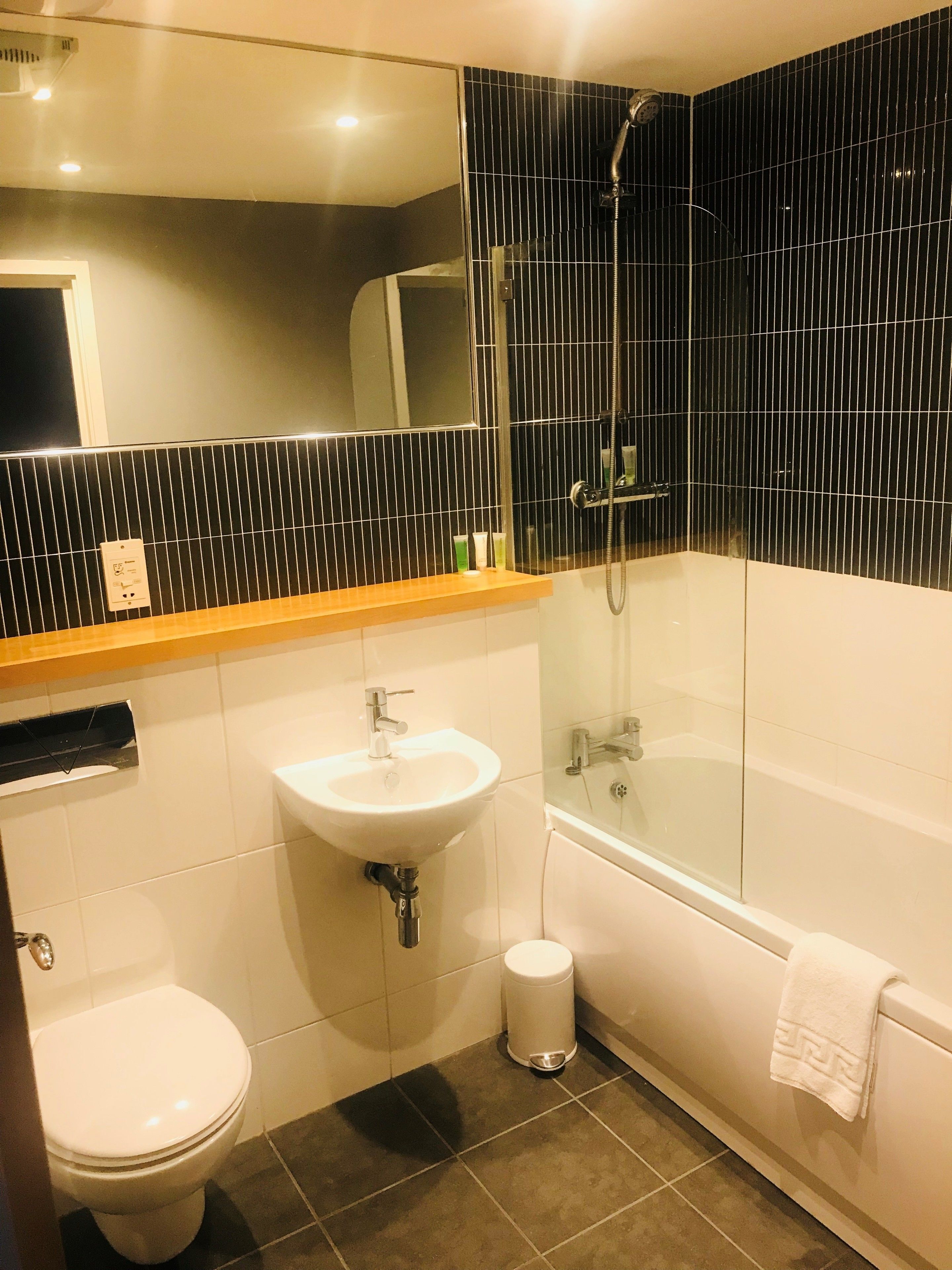 Ein modernes Badezimmer mit einer Glaskabine zur Dusche, einem weißen Waschbecken und einer Toilette.