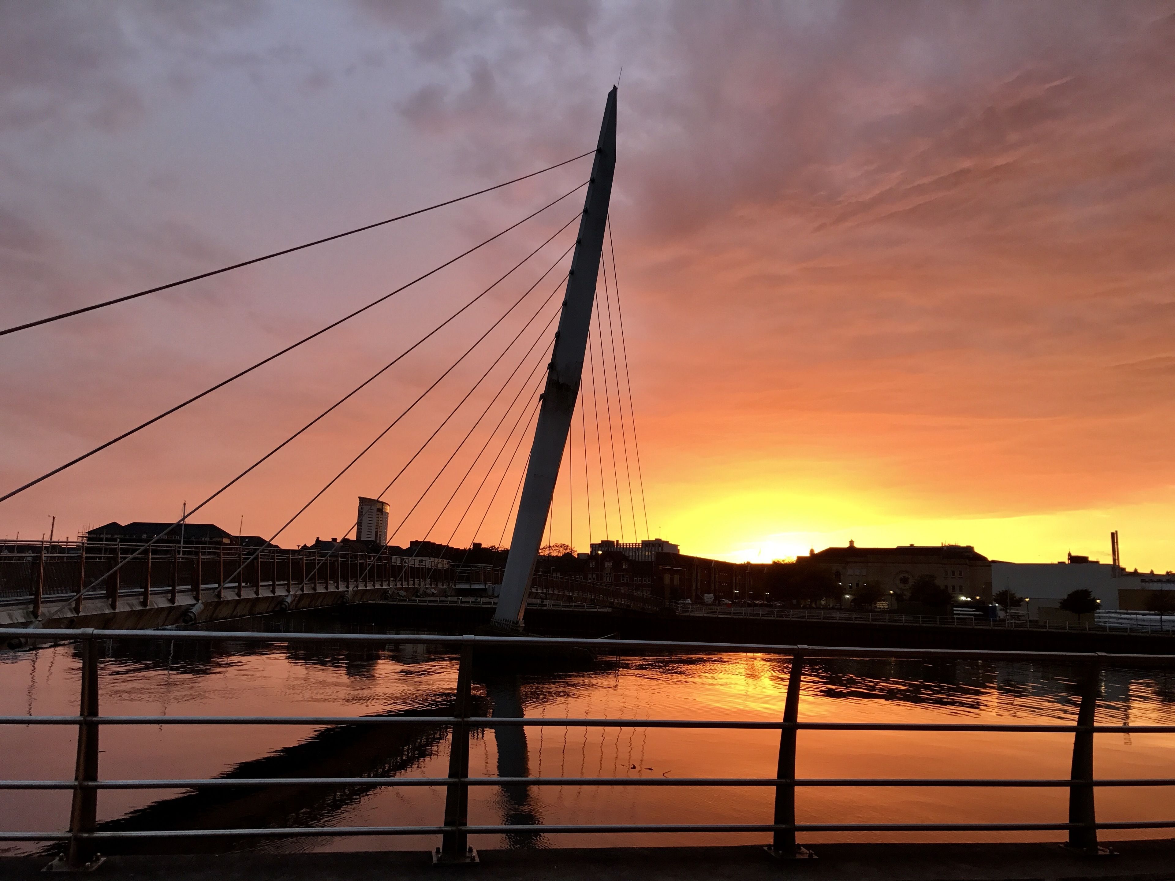 Un puente atirantado con vistas despejadas de la puesta de sol sobre una masa de agua.