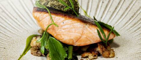 A plate of food with salmon, greens, and sauce.