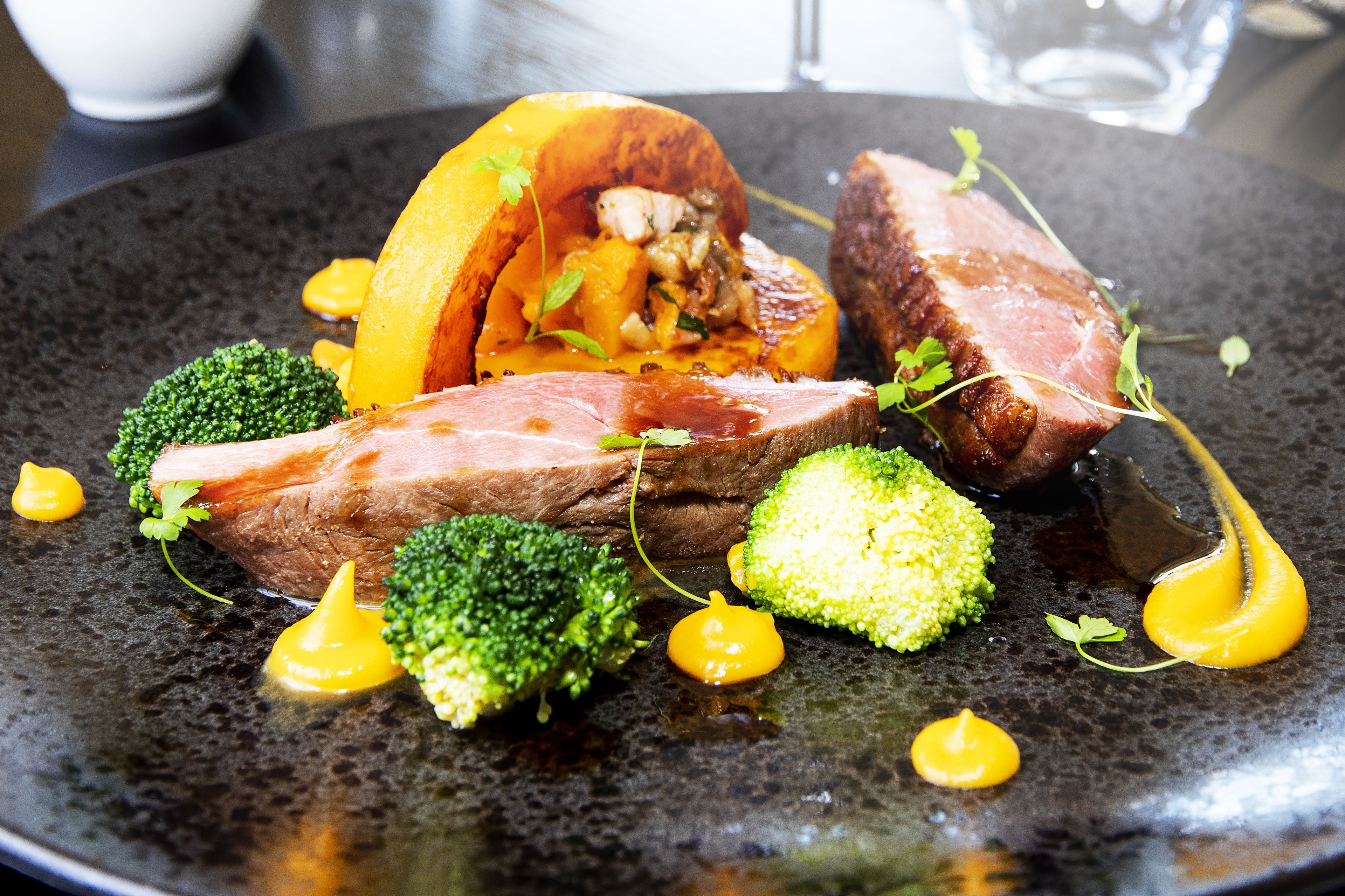A plate of food with meat, broccoli, and a sauce.