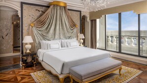A luxurious bedroom with a canopy bed, large windows, and a chandelier.