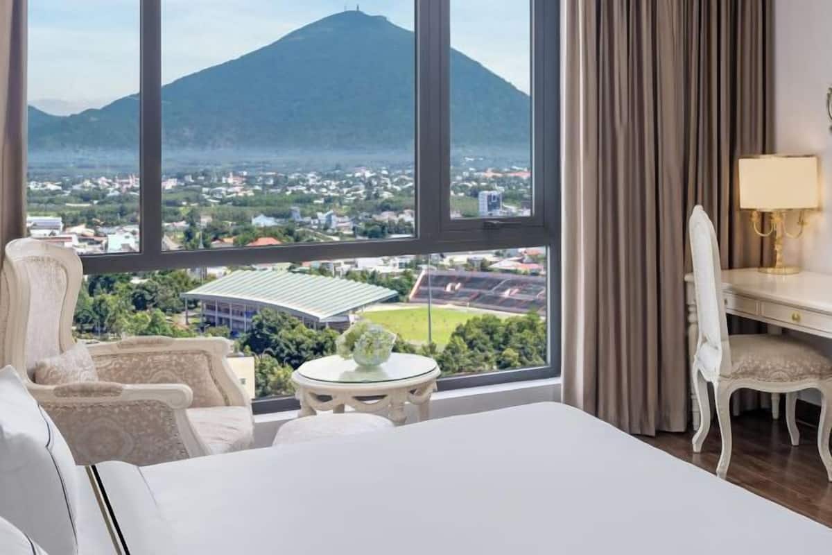 Una habitación de hotel con un ventanal grande, una cama, un escritorio y una silla.
