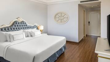 A neatly made bed with a tufted headboard, a bedside table with a lamp, and a round wall clock.