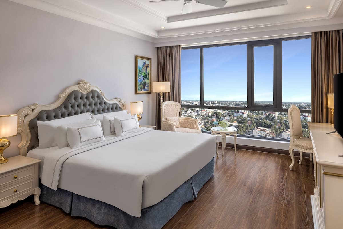 Amplia habitación de hotel con una cama grande, un escritorio y vistas a la ciudad.