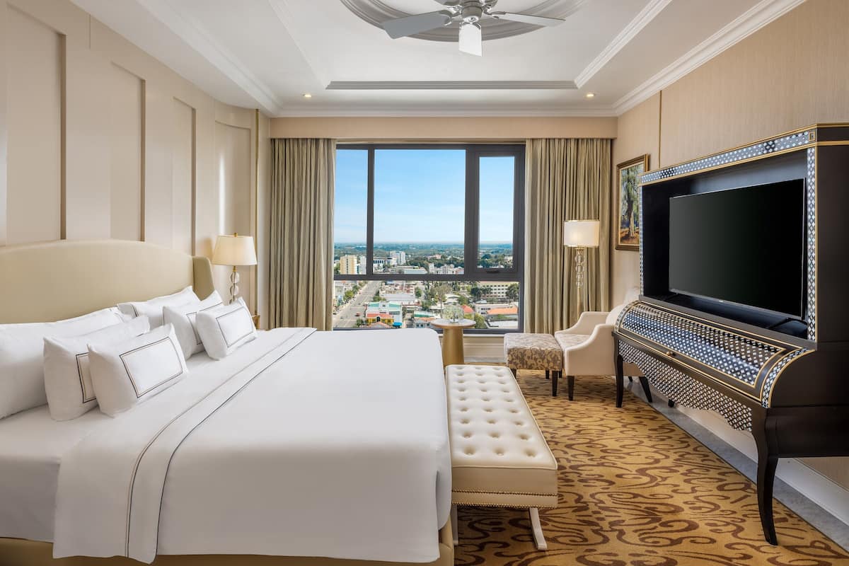 Una habitación de hotel con una cama grande, televisión, escritorio y vistas a la ciudad.