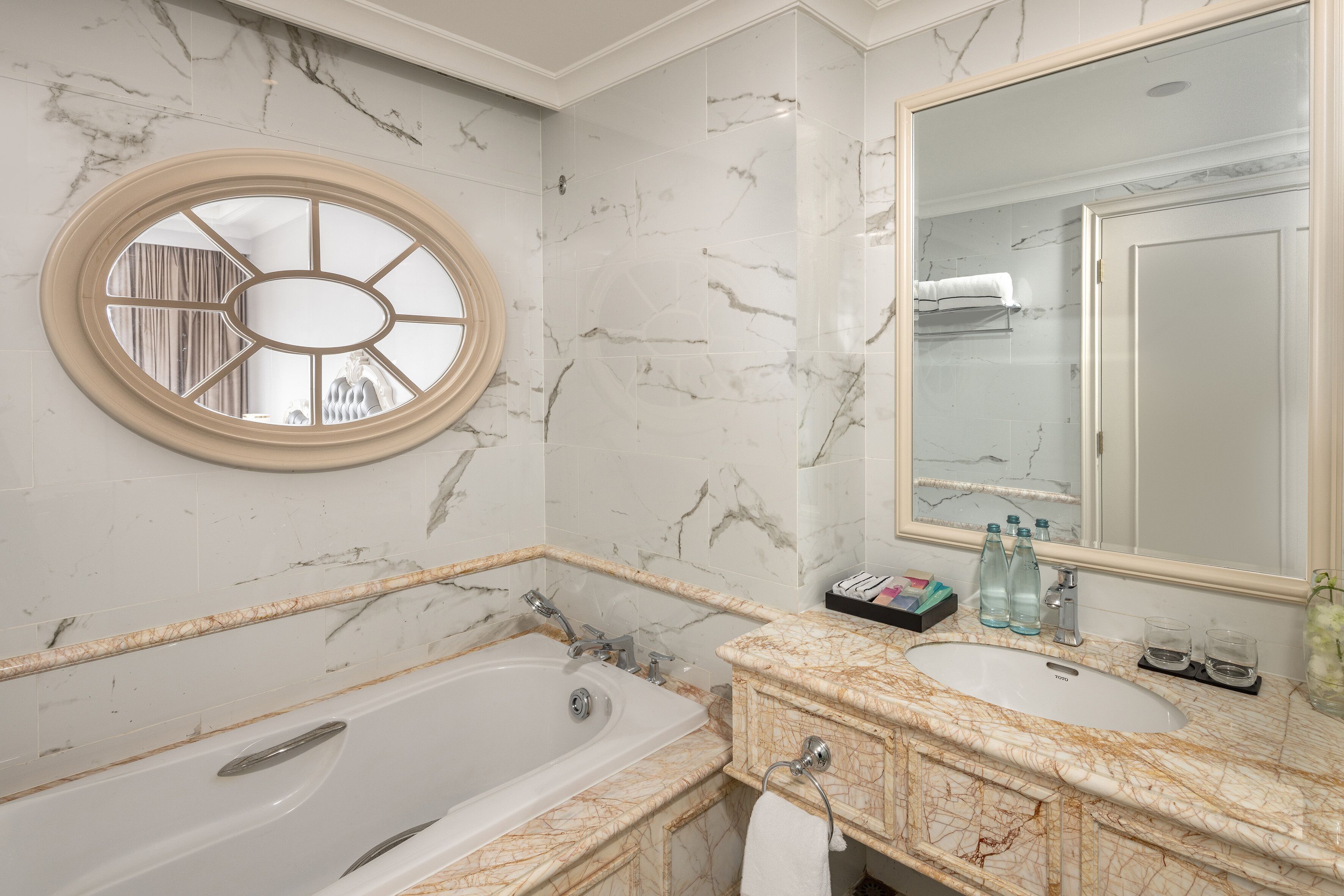 A bathroom with a bathtub, a sink, a mirror, and a window with a decorative frame.