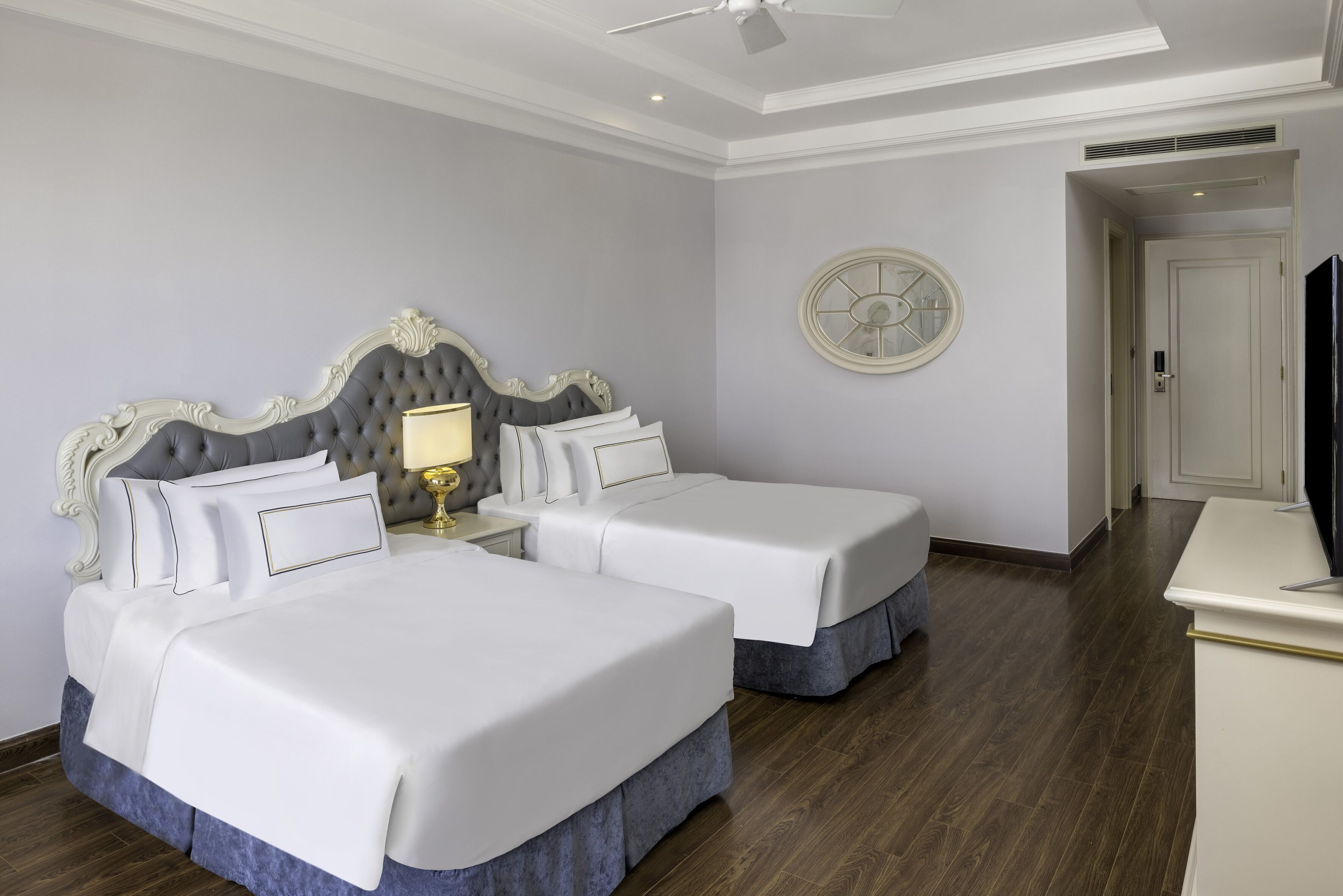 Une chambre d’hôtel avec deux lits, un ventilateur de plafond, une horloge et un téléviseur.