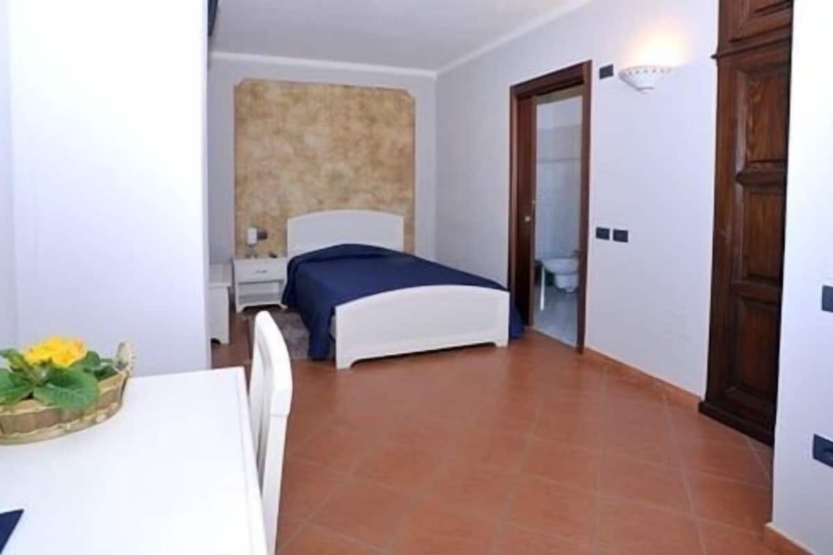 Un dormitorio con cama, mesita de noche y velador.