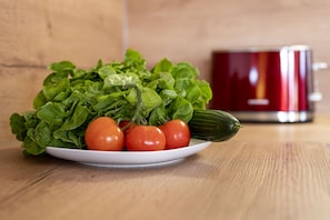 A plate of fresh vegetables including lettuce, tomatoes, and a cucumber on a wooden table.