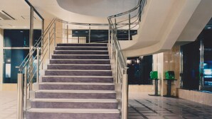 Een modern interieur met een gebogen trap, metalen leuningen en een glazen liftput.