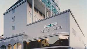 Een modern gebouw met een bord waarop 'Harbor Plaza' staat. Het heeft een opvallende entree met glazen deuren en een plat dak.