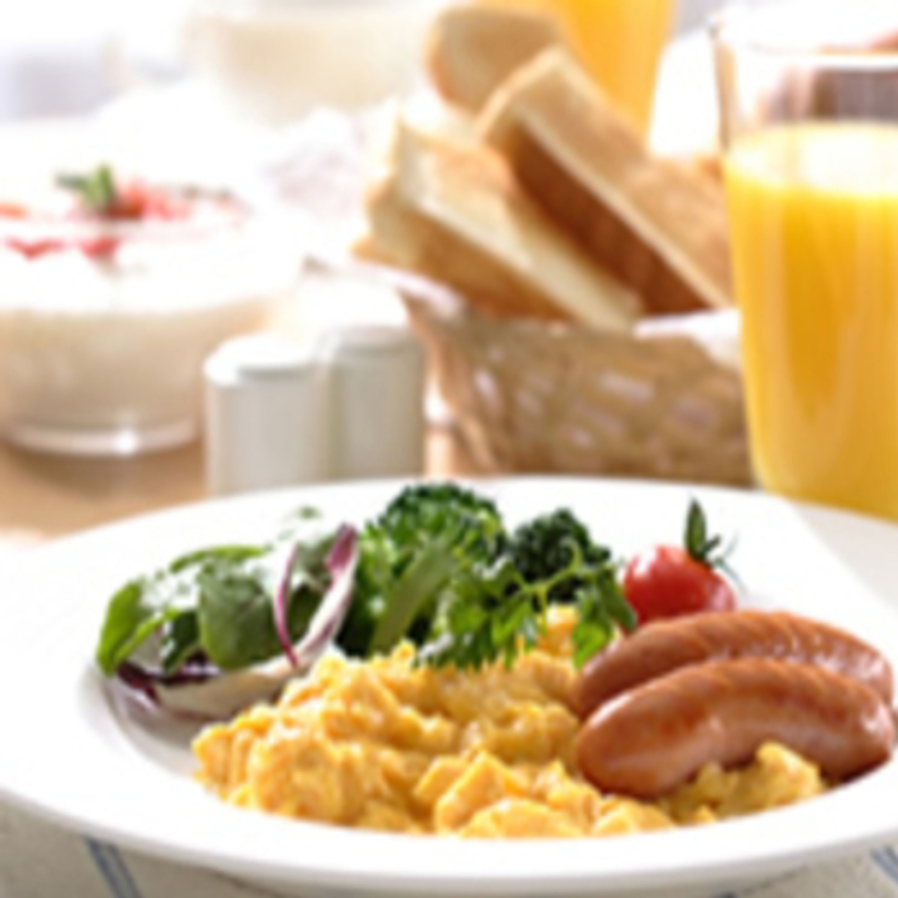 A breakfast plate with scrambled eggs, sausage, and vegetables.
