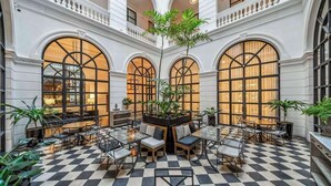 Un espacio interior amplio con piso a cuadros, ventanas arqueadas grandes y diversas disposiciones de asientos.