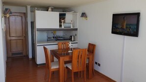 A compact kitchen with a dining area, a refrigerator, a sink, and a microwave. - Departamento Mares de Concon (Concon)