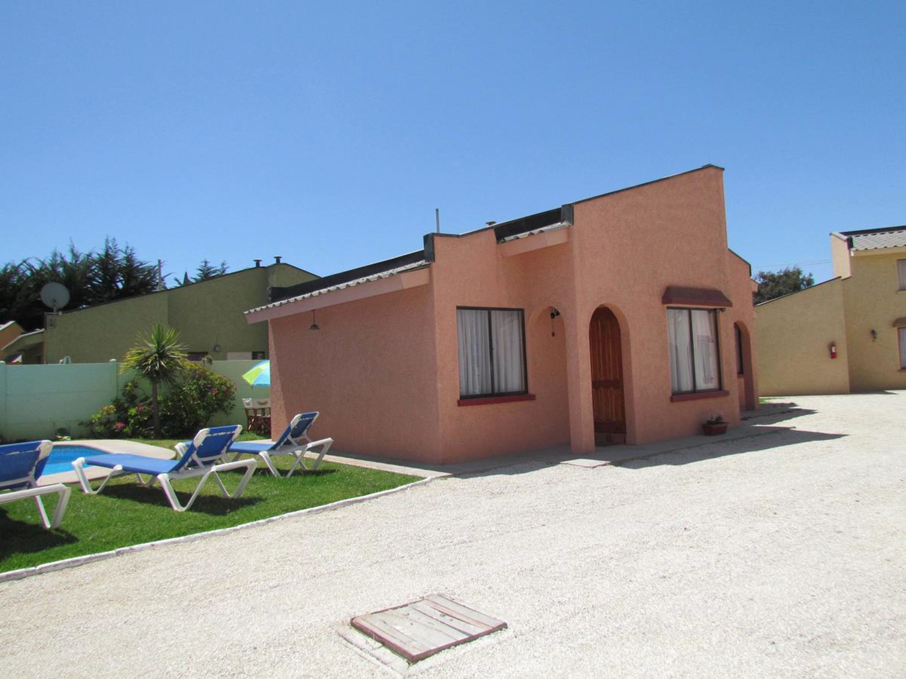 Un edificio pequeño con piscina y sillones de descanso.