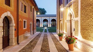 A courtyard with a stone pathway, arches, and potted plants.