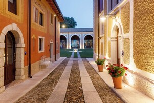 Un cortile con vialetto in pietra, archi e piante in vaso.