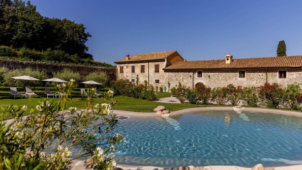 A pool area with lounge chairs and a stone building in the background.