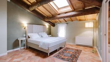 A bedroom with a skylight, a bed, a nightstand, a radiator, and a patterned rug.