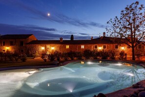 A large, well-lit swimming pool with a stone facade building in the background. - Villa Padovani - Villa Veneta Relais de Charme (Pastrengo)