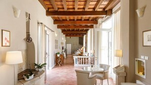 A spacious hallway with a wooden ceiling, a dining area with a table and chairs, and a kitchen in the background.