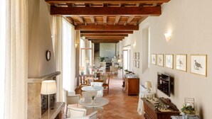 A spacious living area with a high wooden ceiling, a fireplace, and a dining area with white furniture.