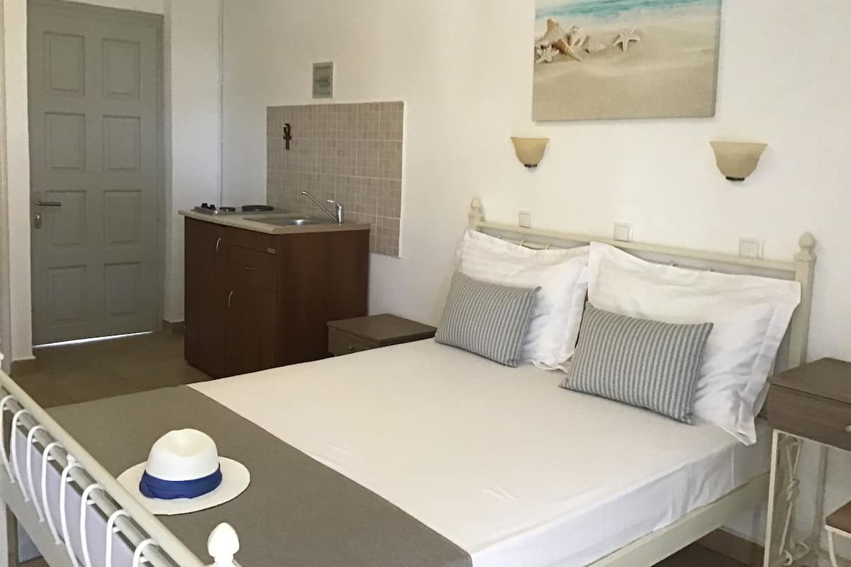 Ein Schlafzimmer mit Bett, Nachttisch, Kommode, Waschbecken und einem Bild von einer Strandansicht.
