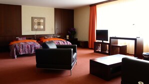 Habitación de hotel con dos camas, un sofá, un televisor y un escritorio.
