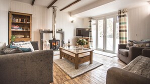 A cozy living room with a fireplace, a television, and comfortable seating. - Lusty Glaze Beach Accommodation (Newquay)