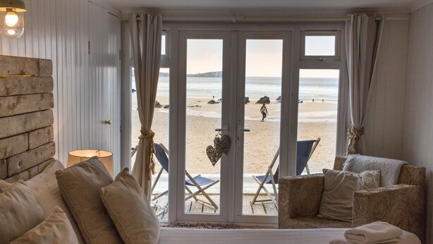 A room with a bed, a chair, and a view of the beach. - Lusty Glaze Beach Accommodation (Newquay)