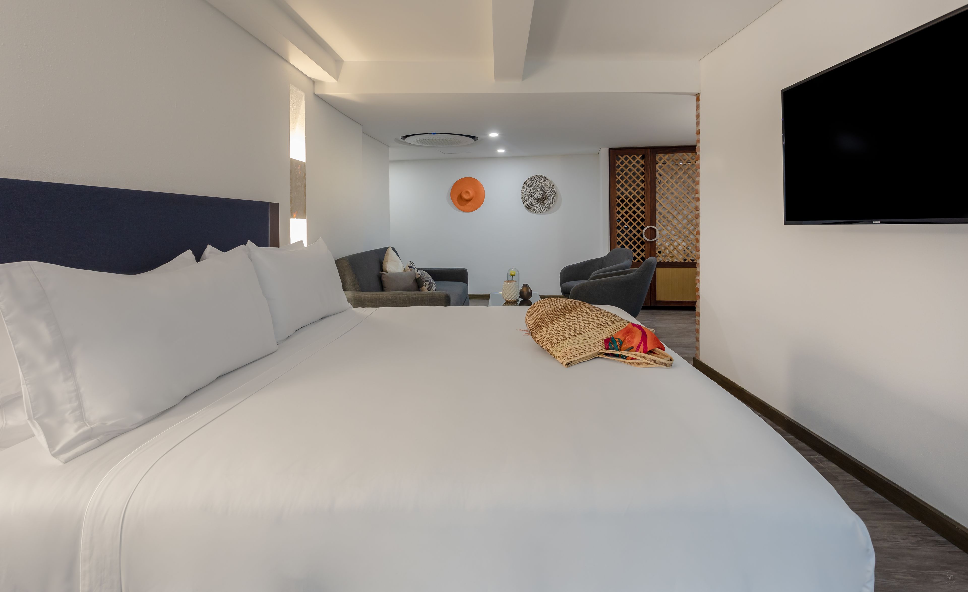 Ett modernt hotellrum med en stor säng, en soffa, en TV och en dekorativ vägg.