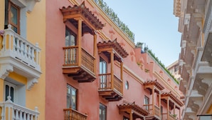 A row of pink and yellow buildings with wooden balconies and doors. - Hotel Santa Catalina By OxoHotel (Cartagena)