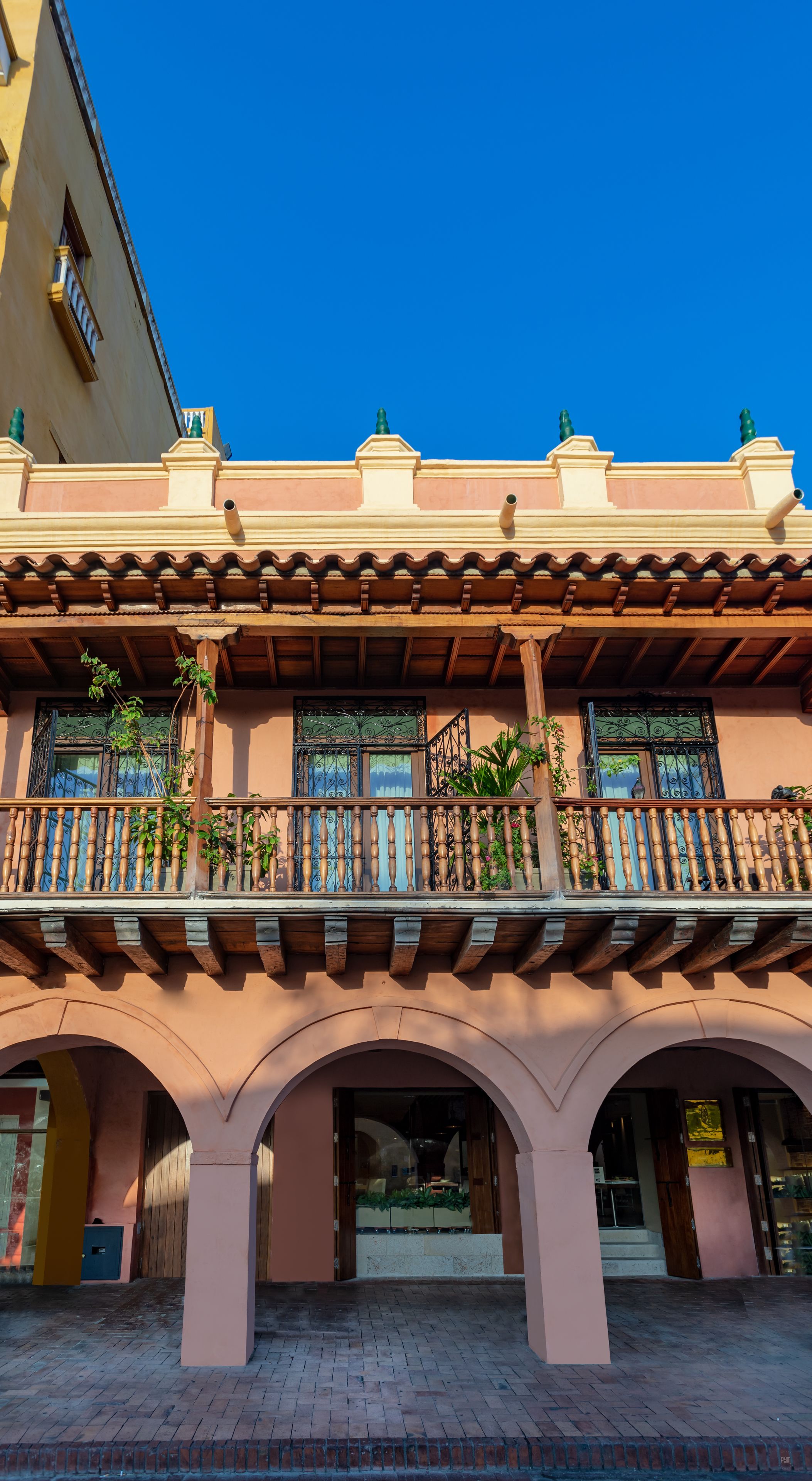 Un bâtiment doté d’un balcon, d’arcades et surplombant un ciel d’un bleu limpide.
