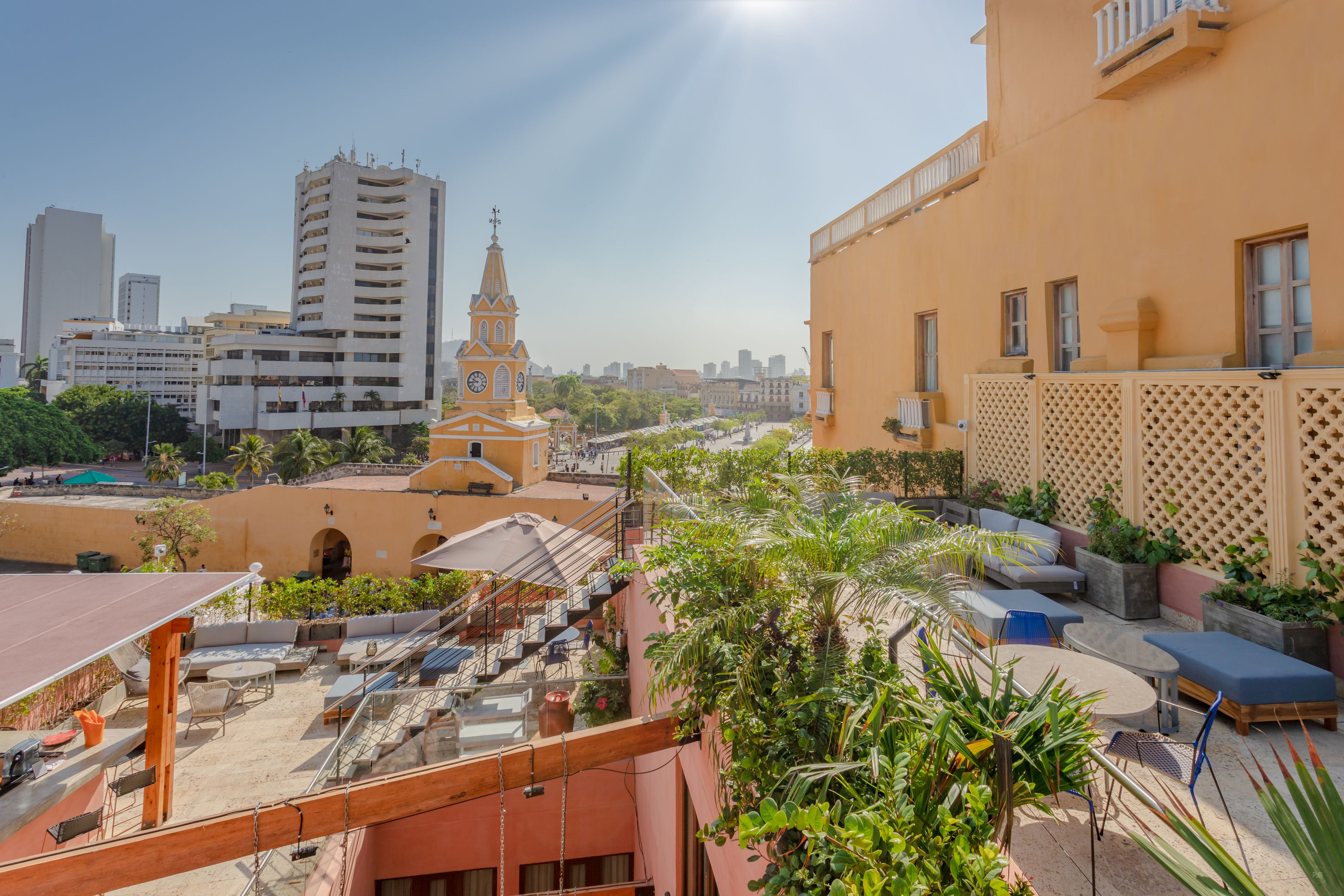 A rooftop terrace with outdoor seating, a clock tower, and a view of the cityscape.