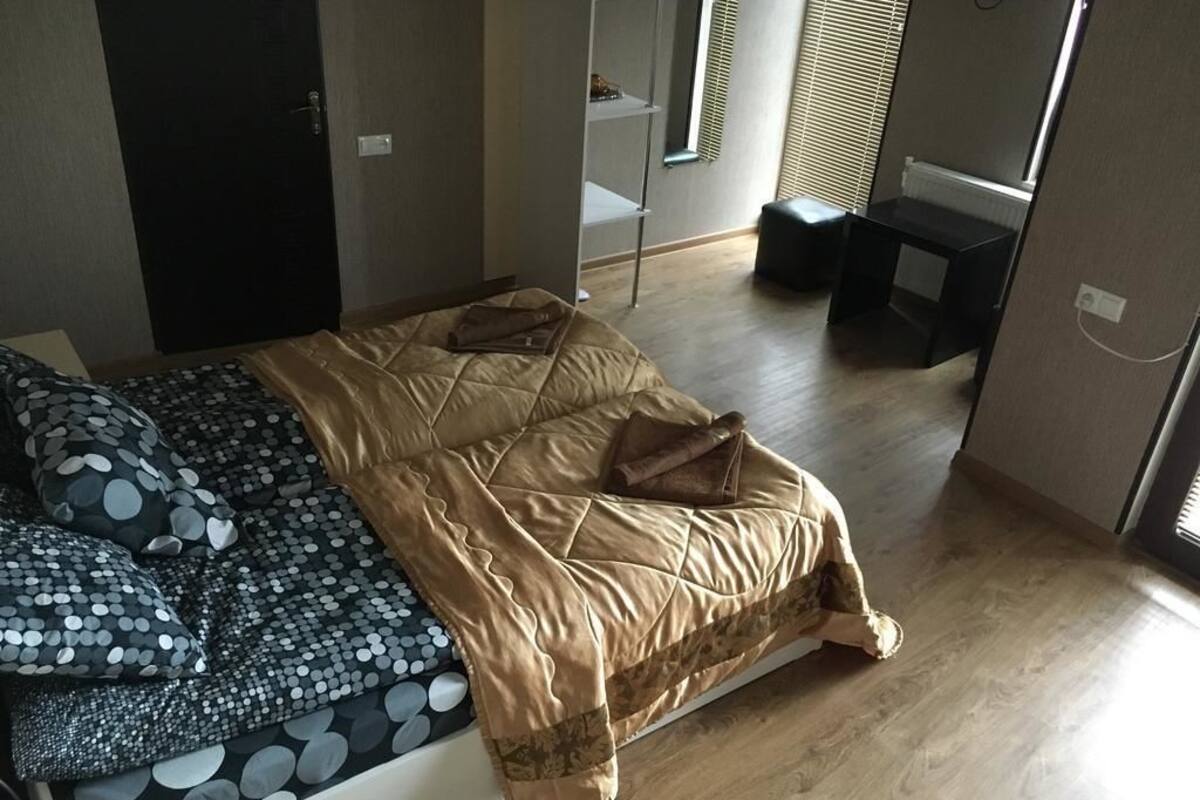 A bedroom with a bed, a desk, and a shelving unit.
