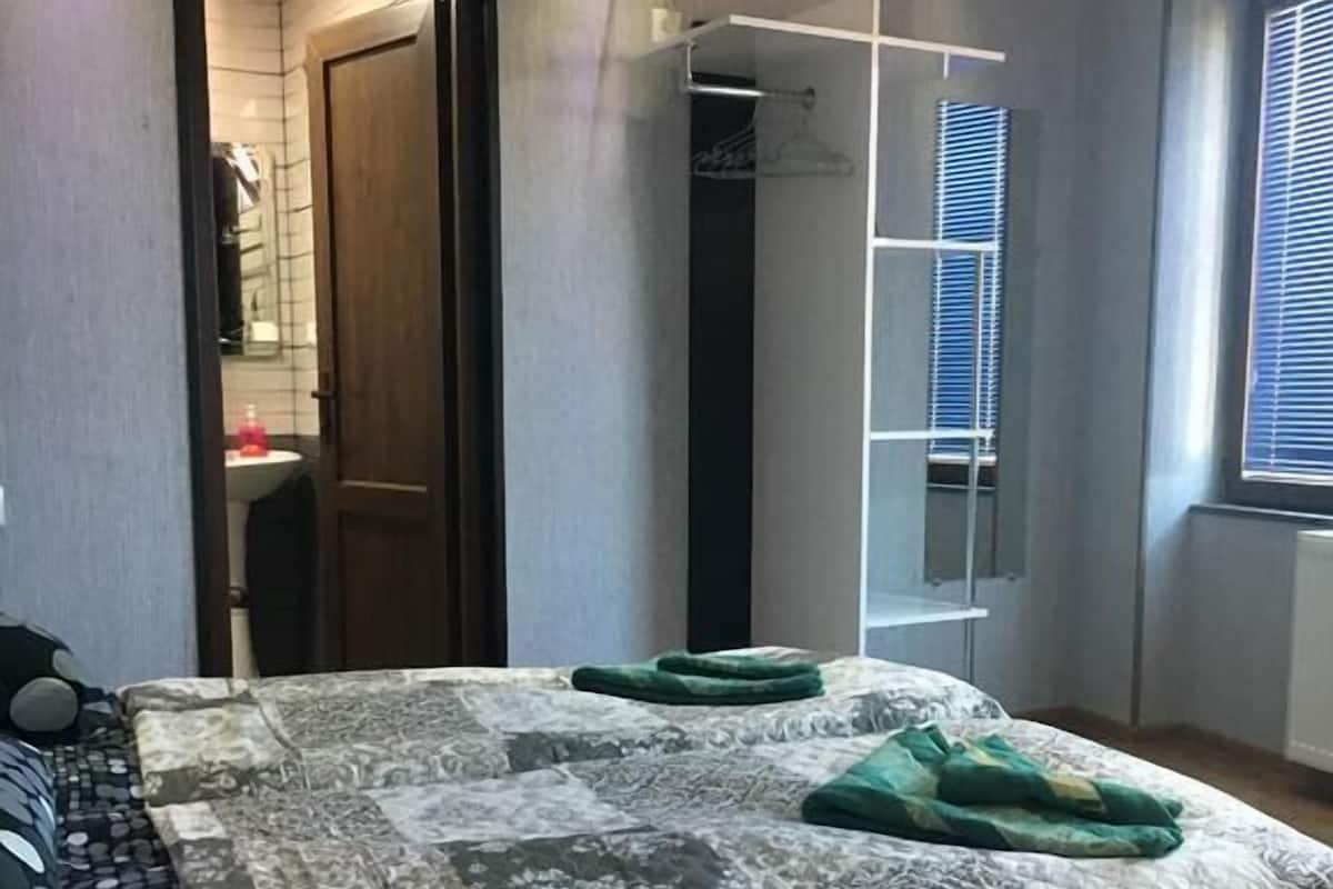 A bedroom with a bed, a wardrobe, a mirror, and a window.