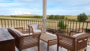 A wooden bench and table set on a balcony with a view of a rural landscape. - Casa Rural La Dueña (El Pobo de Duenas)