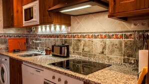 A kitchen with wooden cabinets, a microwave, a toaster, a sink, and a dishwasher. - Casa Rural La Dueña (El Pobo de Duenas)