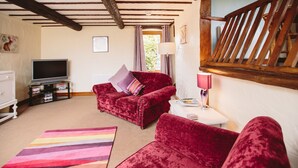 A living room with a red sofa, a television, and a striped rug. - Low Barn Cottage (Brampton)