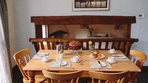 A wooden dining table set with plates, cups, a cake, and a pitcher. - Low Barn Cottage (Brampton)