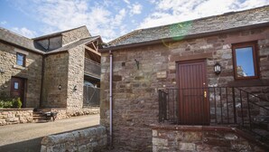 A stone cottage with a wooden door and a small balcony. - Low Barn Cottage (Brampton)