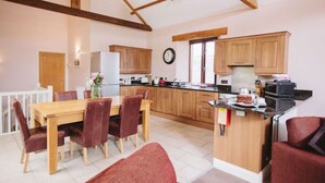 A spacious kitchen with wooden cabinets, a dining area with a table and chairs, and a visible clock on the wall.